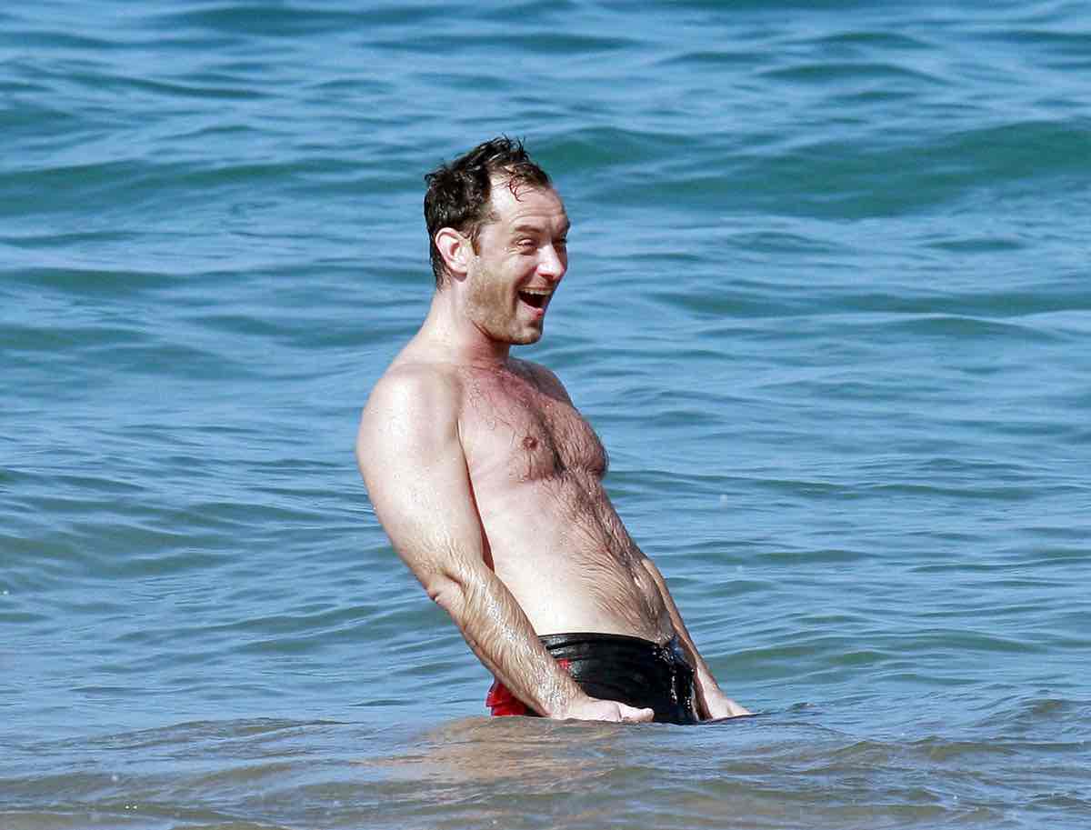 British actor Jude Law taking a dip in the ocean and riding some waves whil...
